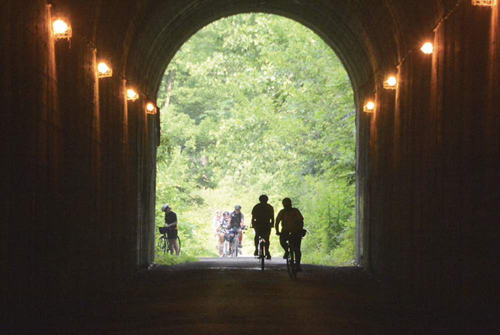 A bike path through a tunnel with bikers biking on it.